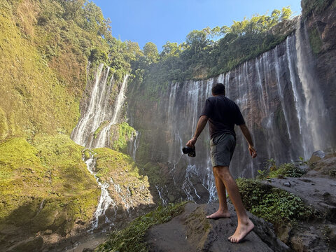 Man photographing tumpak sewu waterfall in java