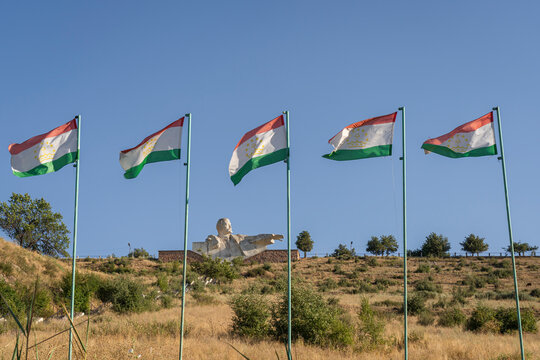 Scenic late afternoon rural view of tajik flags and soviet era Lenin statue on reservoir dike, Istaravshan, Sughd, Tajikistan