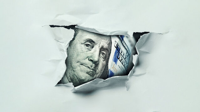 Chewed paper reveals a close view of a hundred dollar bill with the face of Benjamin Franklin
