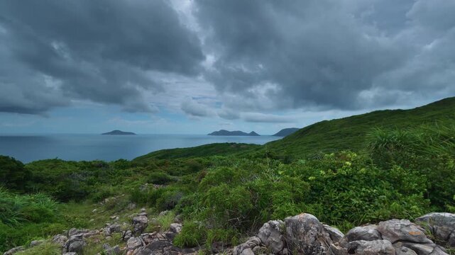 Timelapse of low drifting rain clouds over the lush landscape of Con Son Island, with islands of the Con Dao Archipelago visible in the distance.