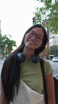 Young asian woman with glasses smiling on a city street