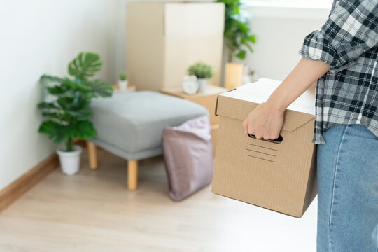 Moving house, relocation. Woman hold carton box contain equipment for new condominium, inside the room was a cardboard box containing personal belongings and furniture. move in the apartment