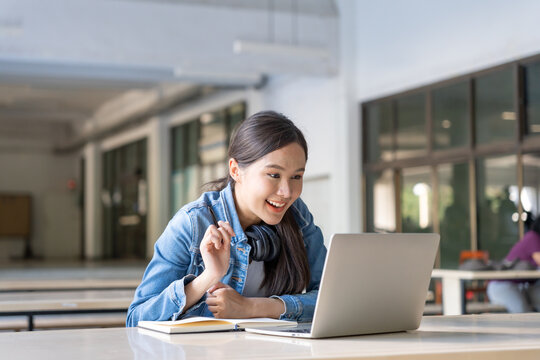 Beautiful Asian woman female student excited checking language test results on laptop. Smile girl happy study online. book in college campus. Portrait female on international Asia University.