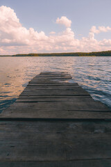 Fototapeta premium Wooden jetty on water with scenic clouds