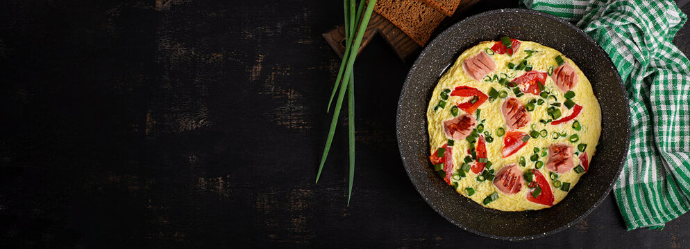 Homemade Omelet with Sausage, Tomatoes and Green Onion in Frying Pan. Top view, banner