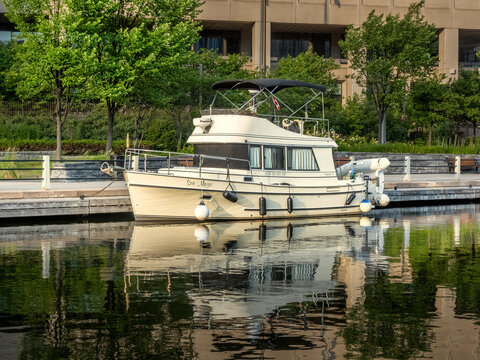 Ottawa, ON, Canada - Sept 14, 2026: The Sea Magic cabin cruiser boat docked along the Rideau Canal with reflections in calm water.