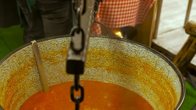 Traditional hungarian goulash soup cooking in cauldron. Delicious and hearty hungarian goulash soup simmering in a large traditional cauldron over a fire at an outdoor christmas market