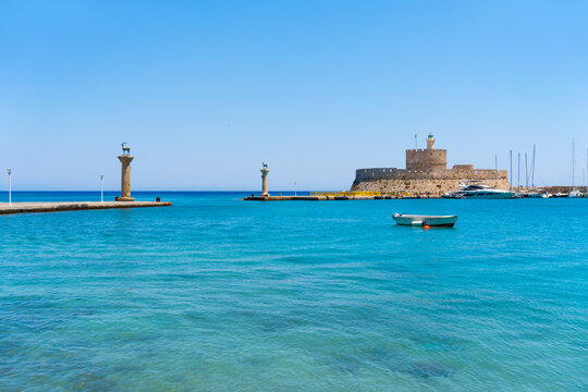 Old port of Rhodes island, Greece. View of St. Nicholas fort and deers statues. Blue sea and the blue sky at sunny day.