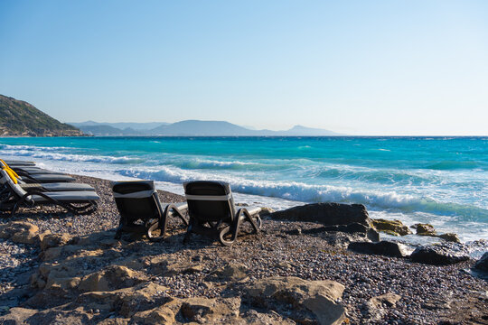 Beautiful beach with turquoise water in Rhodes island, Greece. Sunbeds on the beach. Blue sea and the blue sky at sunset.