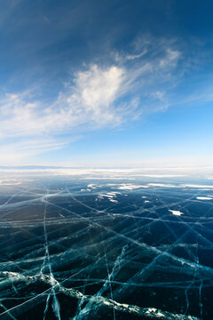 Transparent blue ice with cracks on Baikal lake in winter. Baikal, Siberia, Russia. Beautiful winter landscape