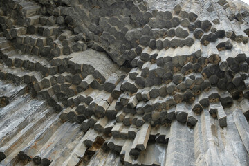 Geological formations of basalt columns in Armenia display distinct hexagonal shapes and textured surfaces, creating a striking natural landscape © Anat art
