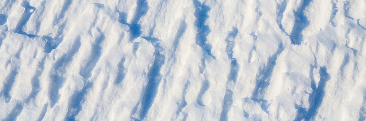 Beautiful winter background with snowy ground. Natural snow texture. Wind sculpted patterns on snow surface. Wide panoramic texture for background and design. © Andrei Stepanov