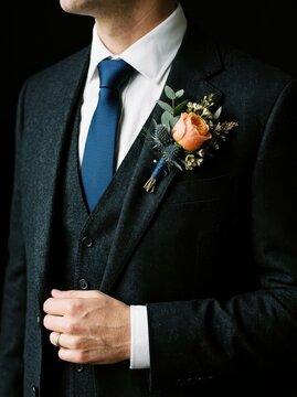 Elegant Groom in Dark Three-Piece Suit with Peach Rose Boutonniere and Blue Tie