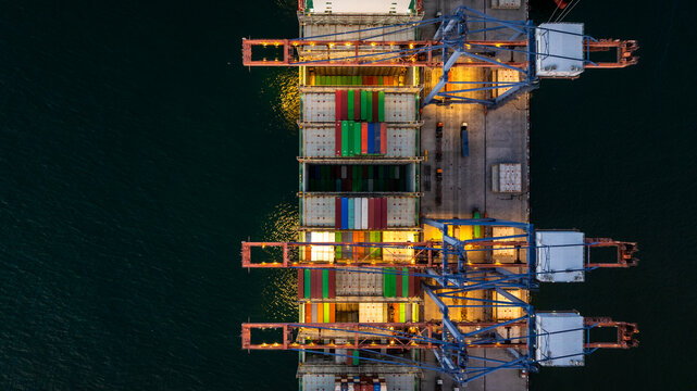 Aerial view container cargo ship loading unloading at night, Container cargo ship import export sea port, Global trade business container cargo ship freight shipping commercial trade logistic.