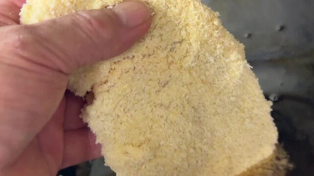 Cook putting a panko breaded pork cutlet into hot oil to make katsudon at an izakaya in Japan, close up