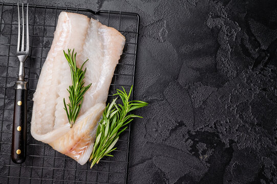 Uncooked Atlantic cod fillet, raw fish ready to be seasoned and transformed into a delicious meal. black background. top view