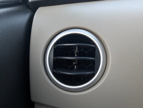 Circular car air conditioning vent integrated into a textured dashboard