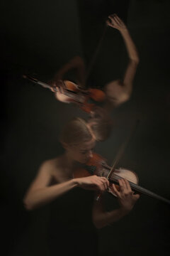 Vertical shot of Caucasian young adult woman playing violin with motion blur effect representing classical music performance. Image suited for concert promotion and musical arts marketing