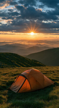 Camping tent in mountains during golden sunset creating starburst