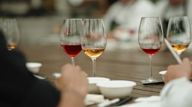 People taking part in a tea tasting event sampling different infusions with focus on the glasses and hands on the table