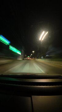 Night highway timelapse showing glowing street lights, moving traffic and colorful light trails from a driving perspective.