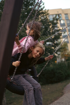 Two young friends playing together on a tire swing