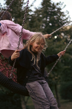 Happy young girls having fun on a large playground swing