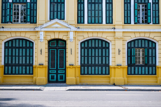 Facade of a yellow colonial building with green shutters