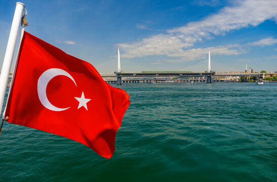 Turkish flag waving on a boat with the Bosphorus bridge and Istanbul cityscape background under a blue sky