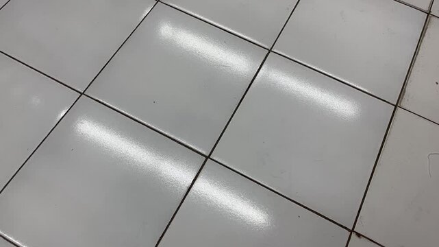 High angle shot of glossy white floor tiles with linear reflections