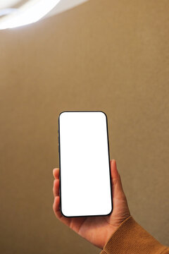 Vertical mockup image of a woman holding mobile phone with blank desktop screen in cafe