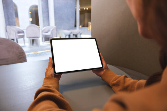 Mockup image of a woman holding digital tablet with blank white desktop screen in cafe
