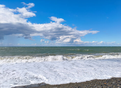 Sea coast, blue sky, summer day, waves rolling onto the shore
