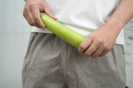Male stands holding a banana, penis health.