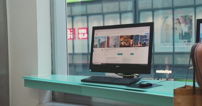 Hong Kong, 18 June 2026 - Hong Kong, 18 June 2026. Computer monitor displaying hotel website on desktop table by window overlooking city street, Ibis Hotel lobby business corner workstation.
