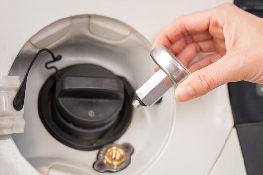 A woman installs an adapter on a gas tank in a car.