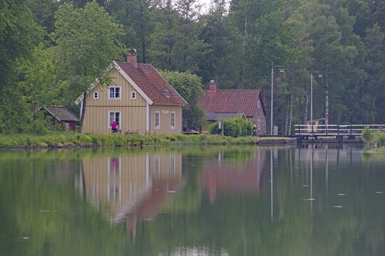 Houses are reflected in a calm body of water in nature, Schleusenw&auml;rterhaus, Sj&ouml;torp, G&ouml;takanal, V&auml;stra G&ouml;talands l&auml;n, Sweden