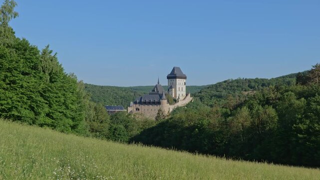 The Karlstejn Castle Czech Republic, zoom out to meadow in forest. Medieval Gothic castle founded in 1348 by King Charles IV.