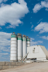 Asphalt concrete plant silos storing bulk materials under blue sky © MexChriss