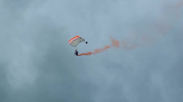 Skydiver with Orange Smoke Trail Performing Aerial Stunts