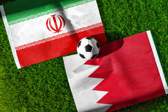 Iran vs. Bahrain football match. National flags on green grass with soccer ball in the middle. Football background for international match.