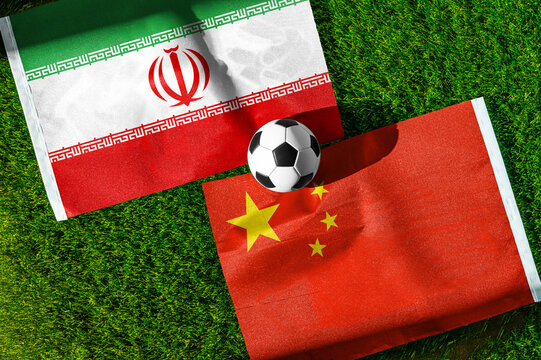 Iran vs. China football match. National flags on green grass with soccer ball in the middle. Football background for international match.