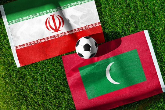 Iran vs. Maldives football match. National flags on green grass with soccer ball in the middle. Football background for international match.