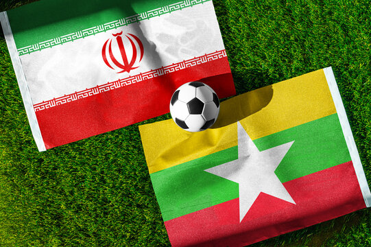 Iran vs. Myanmar football match. National flags on green grass with soccer ball in the middle. Football background for international match.