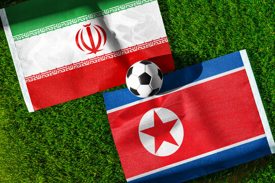 Iran vs. North Korea football match. National flags on green grass with soccer ball in the middle. Football background for international match.