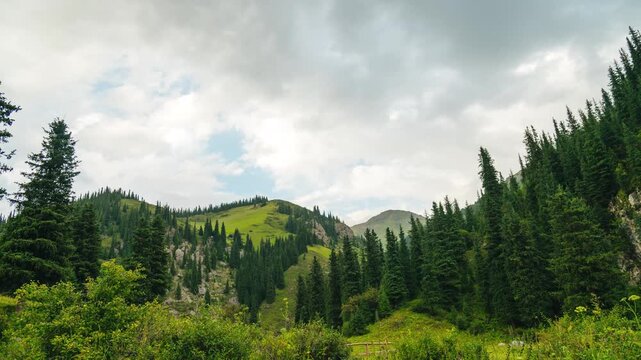 White clouds are moving quickly across the blue sky above the mountains, time‑lapse.