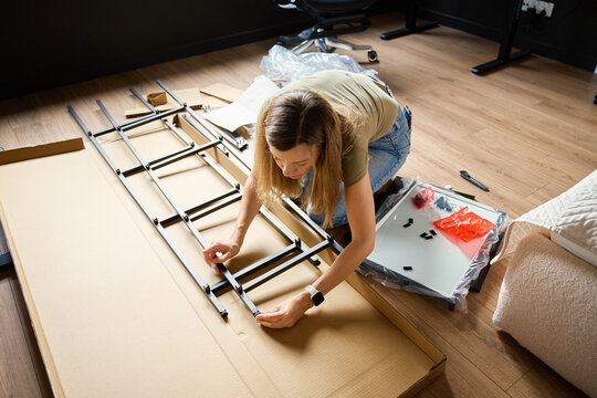 Woman assembling shelving frame on floor at home