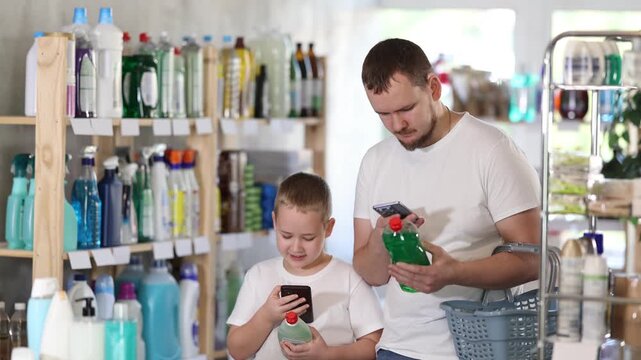 Dad teaches his son to scan QR code on package of dishwashing. Store visitors study product information in mobile app before purchasing, using QR code and smartphone camera . High quality 4k footage
