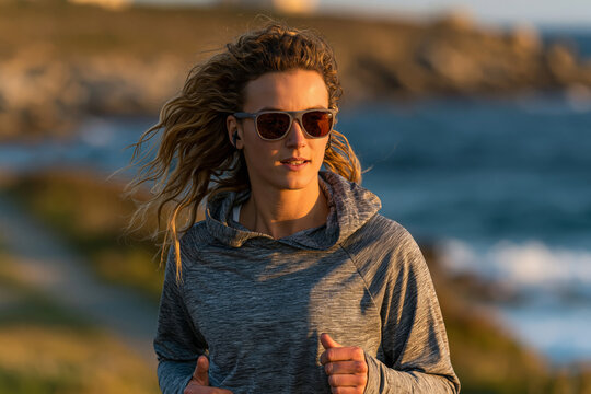 Female runner wearing lightweight UV protective sports shades on a coastal jogging path, early morning sunlight, energetic fitness concept,, perfect for modern design, travel, or lifestyle marketing