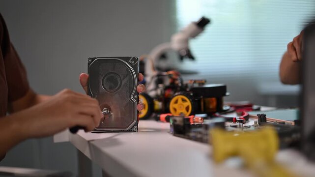 Hands Manipulating Small Mechanical Parts and Tools on Workplace Table